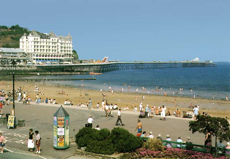Le pier,
                  la plage et sa promenade de Llandudno aux bancs
                  occupés par l'Age d'or...