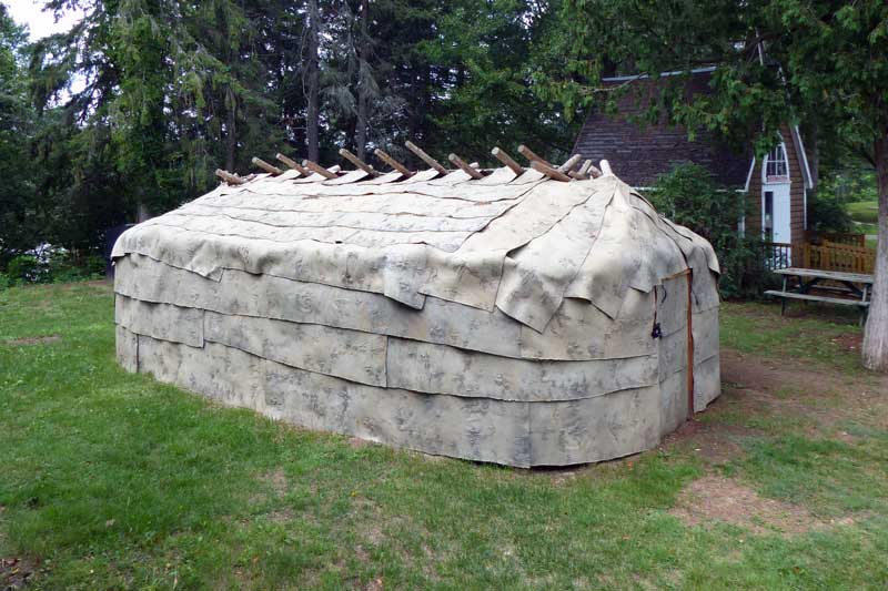 Longue maison commune recouverte d'écorce de boleau
            devant le muéee