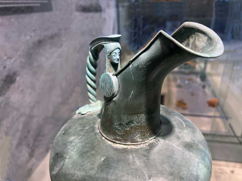 Ioannina-Cruche-a-bec-en-bronze-avec-un-buste-feminin-sur-la-poignee-Atelier-corinthien-Epoque-archaique-(510-490-av.-J-C).